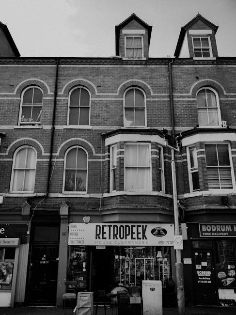 The image depicts the front of a three-story brick building on Kennington Road, with the ground floor occupied by a house clearance and storage business called Retroepk, which has a large sign above t